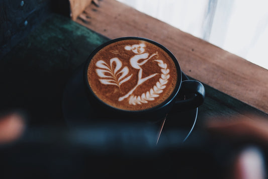 black and brown coffee cup on brown wooden table