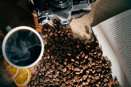 a cup of coffee next to a book and a camera