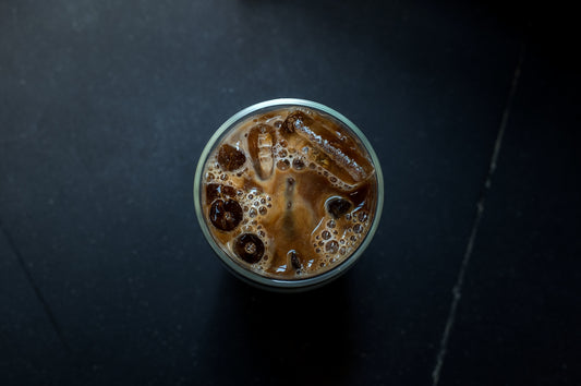 a glass of iced coffee on a black table