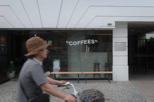 A man riding a bike past a coffee shop