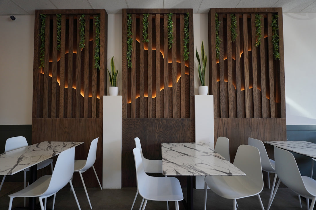 A restaurant with tables and white chairs and wooden screens