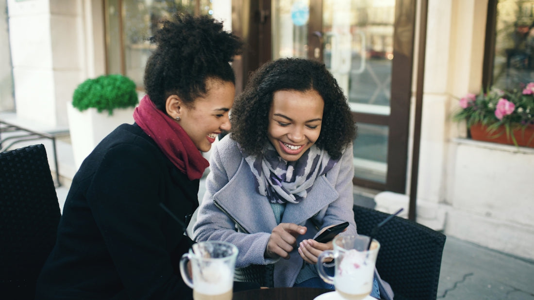 Two women laughing while looking at a phone.
