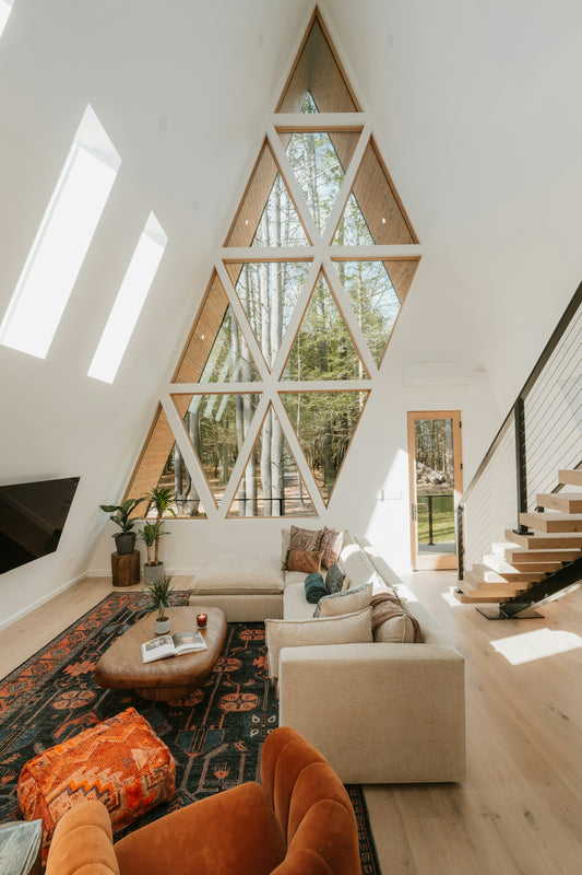 Modern living room with geometric window and forest view