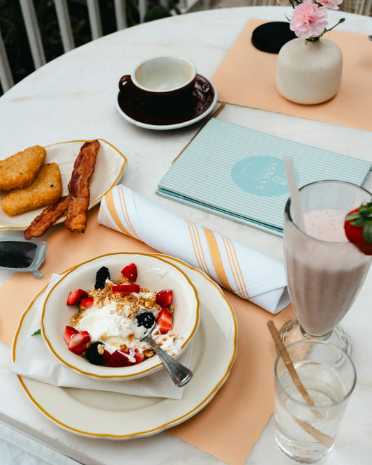 Breakfast spread with yogurt, fruit, bacon, and hash browns.