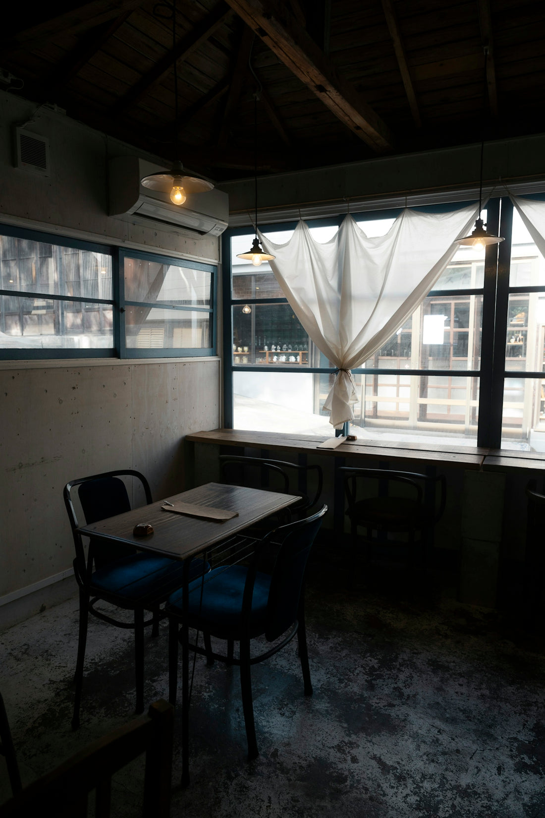 Cozy cafe interior with tables and chairs by window.